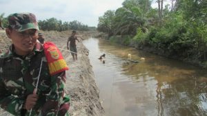 Manfaatkan Sungai Senari Satgas Bawa Kayu Untuk Bangun Jembatan