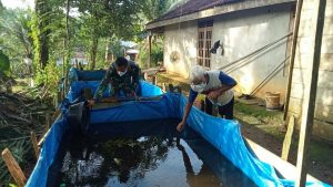 Anggota Satgas Bantu Bersihkan Kolam Ikan Warga