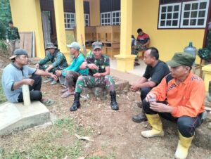 Anggota Satgas Bersama Warga Duduk Santai Sambil Bersenda Gurau Di Sasaran Rehab Sekolah Dasar